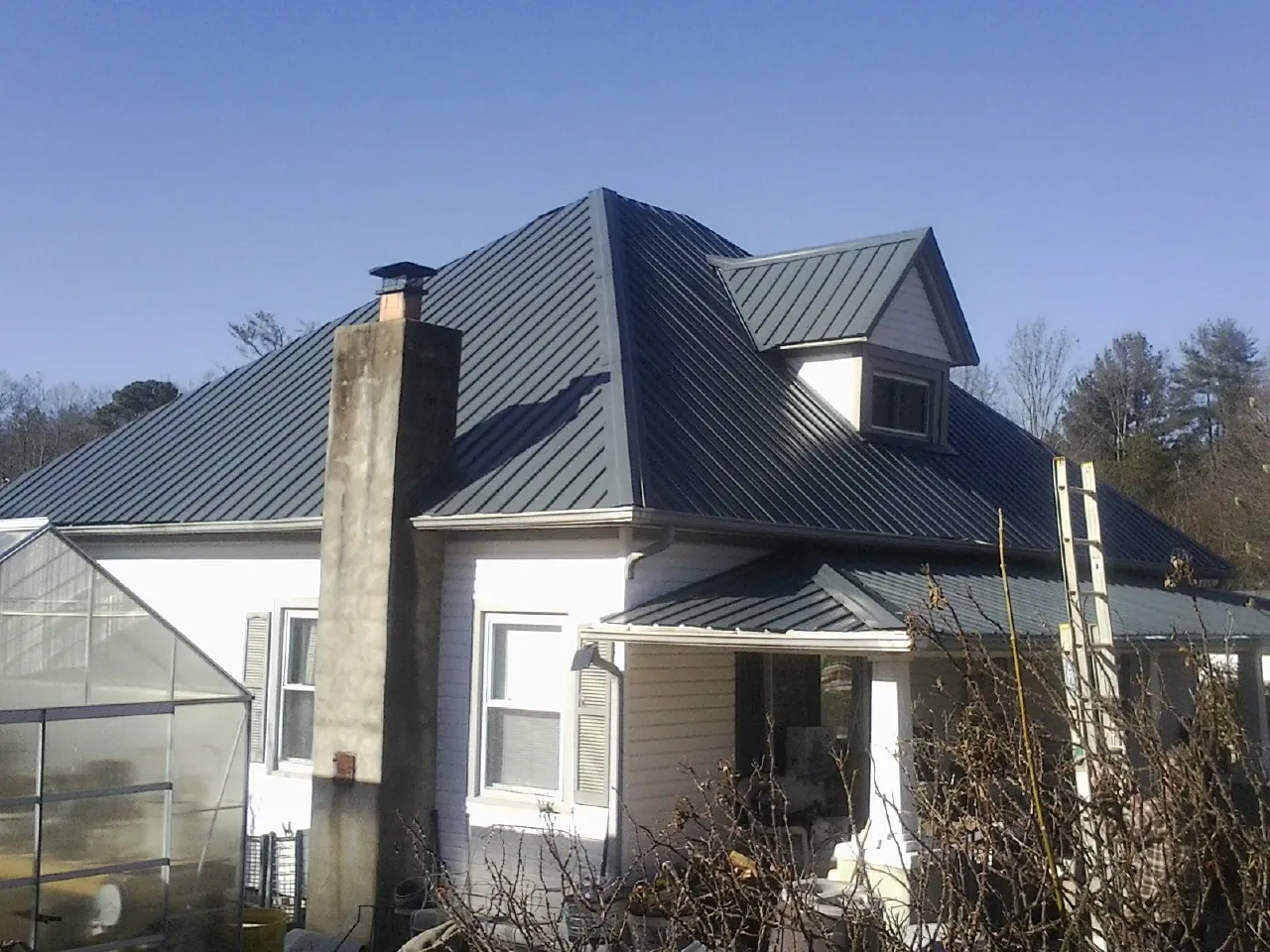 Dark blue standing seam metal roof on a white farmhouse with dormer — Slate & Tile Roof Repair by Roofing Brothers in Waterford