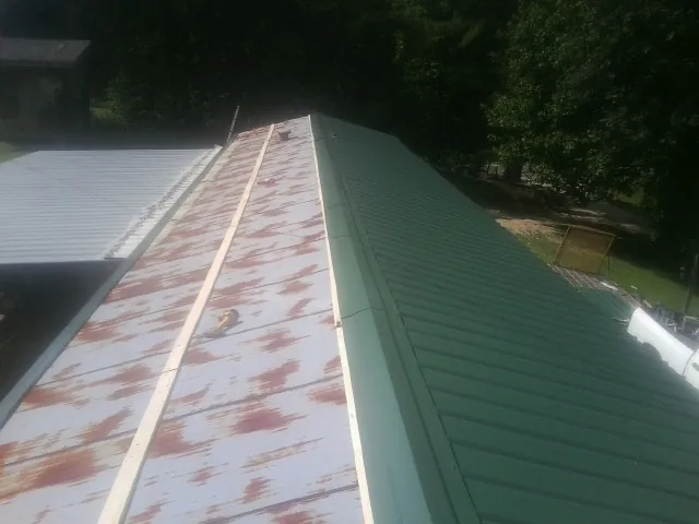 Old rusted panels beside newly installed green metal roofing — Wind Damage Roof Repair by Roofing Brothers in Waterford