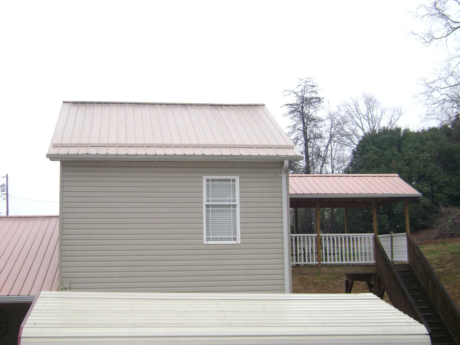 Tan metal roofs on a two story addition and attached porch, from a Roof Replacement job in Waterford